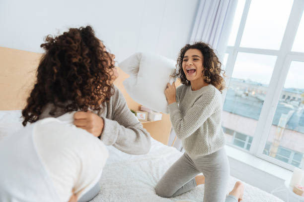 istock Radiant girls having fun and pillow fighting 890604504