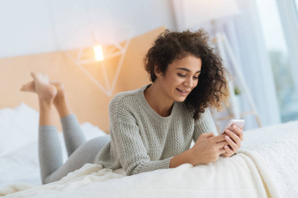 istock Relaxed young lady lying on bed and using her smartphone 890606970