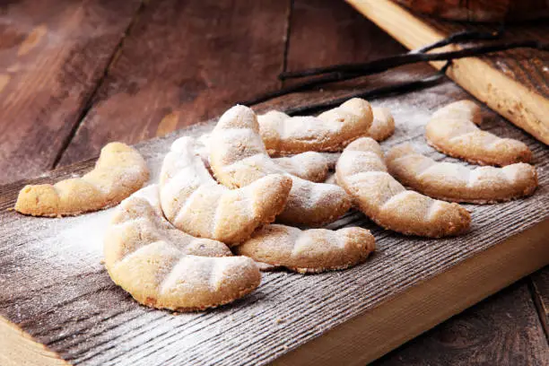 Vanille Kipferl cookies for christmas on brown wooden table with sugar.