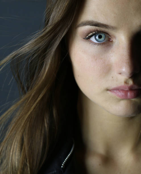 Closeup young woman with blue eyes half face studio on a gray background