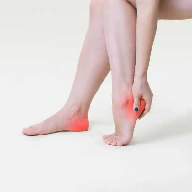 Photo of Pain in woman's legs, massage of female feet on beige background