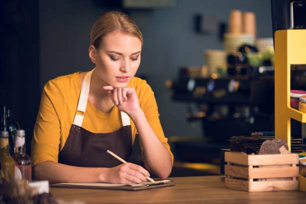 istock Serious female barista writing in clipboard 890629598