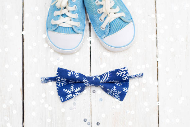 istock Accessories for a little boy, a bow tie and sneakers on a shiny background. Flat lay 890641124