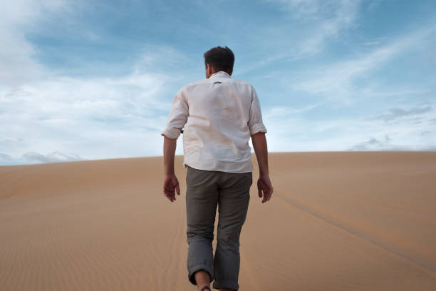 istock Caucasian young man going straight on his way on sandy desert 890641852
