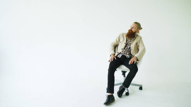 istock Serious bearded man sitting on swivel office chair on white background 890642072