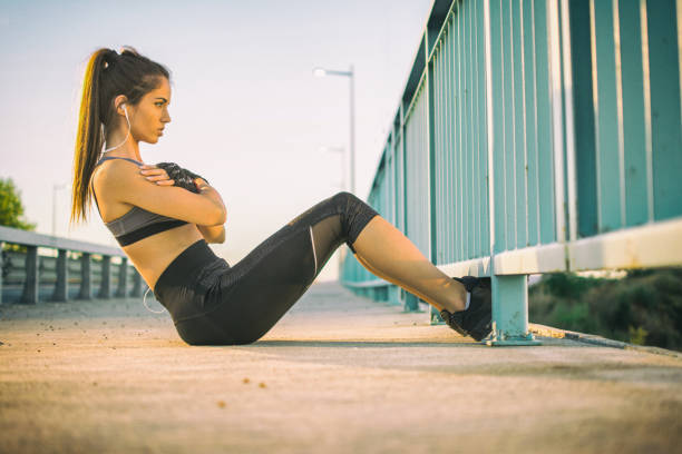 istock Fit young woman doing sit ups on a sidewalk. 890646958