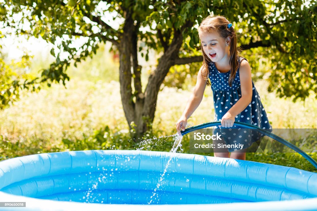 Little girl pouring water into a small pool Swimming Pool Stock Photo