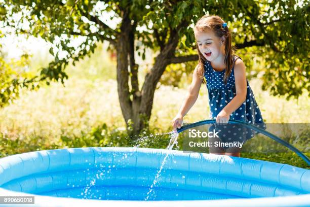 Little Girl Pouring Water Into A Small Pool Stock Photo - Download Image Now - Swimming Pool, Filling, Competition Group