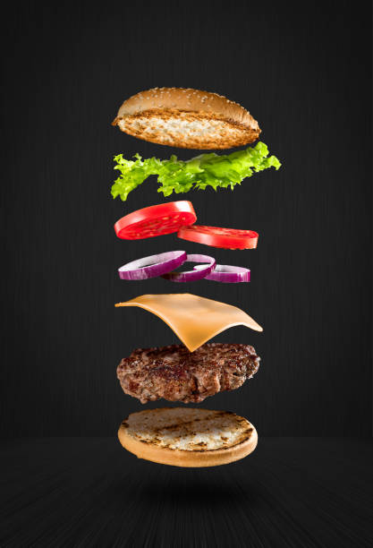 Delicious hamburger with flying ingredients on black background Delicious hamburger with flying ingredients on black background cheeseburger photos stock pictures, royalty-free photos & images