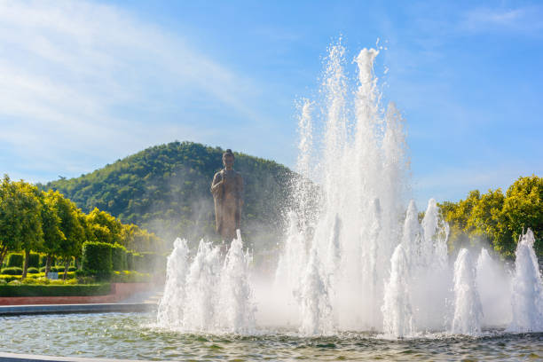 Fountain in a park with green tree and blue sky background