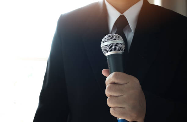istock Journalists filing microphone interviewing to businessman. Smart Reporter taking interview and speech with microphone at presentation in conference, Business seminar concept 890668566
