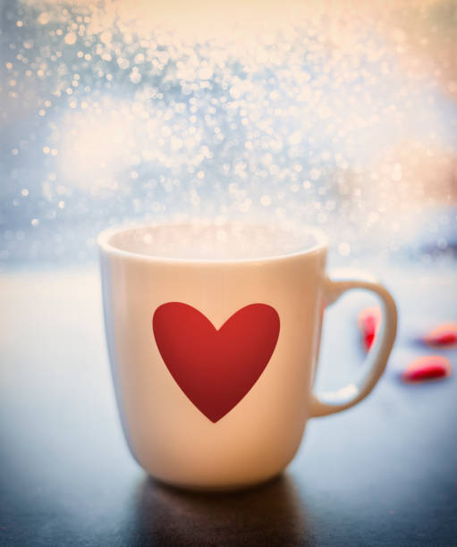 istock Mug with red heart and bokeh at window, close up, front view. 890687260