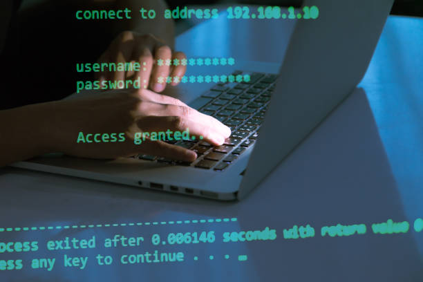 A computer programmer or hacker prints a code on a laptop keyboard to break into a secret organization system. stock photo