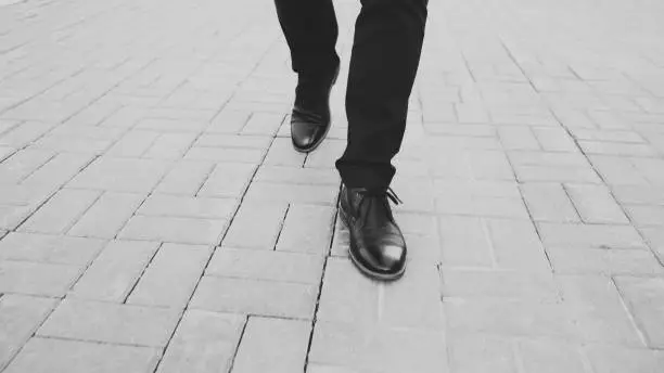 Photo of Closeup view businessman in shoes walking ahead sidewalk at street