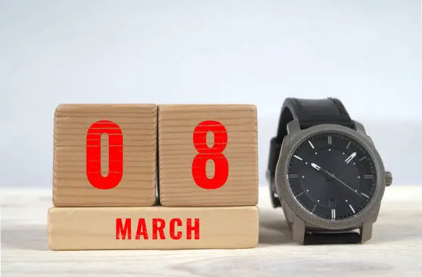 8 march, calendar on wooden blocks with wrist watch