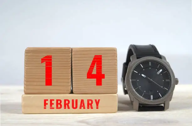14 february, calendar on wooden blocks with wrist watch