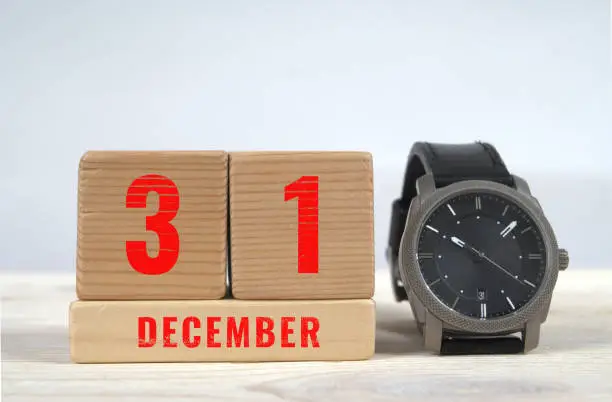 31 december, calendar on wooden blocks with wrist watch