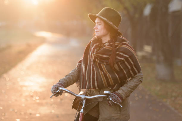istock Ginger woman walking along her bicycle on an autumn day 890741446