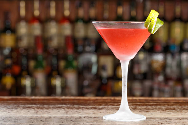 An alcoholic cosmopolitan cocktail is on the bar. Space for text.