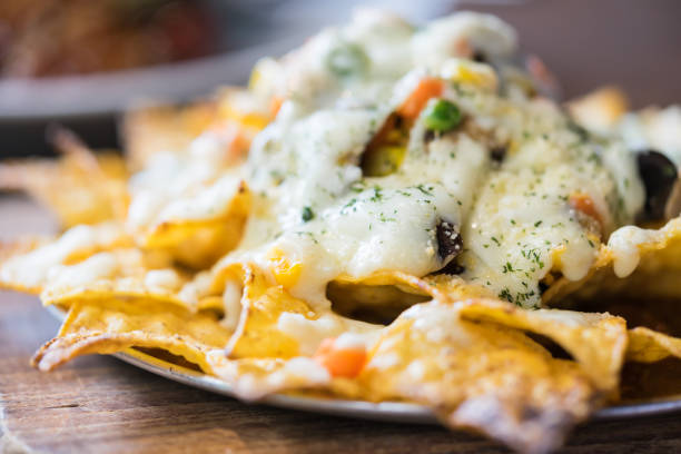 um prato de nachos deliciosa tortilha com molho de queijo derretido e molho. fundo de comida. - chili pepper guacamole food beer - fotografias e filmes do acervo