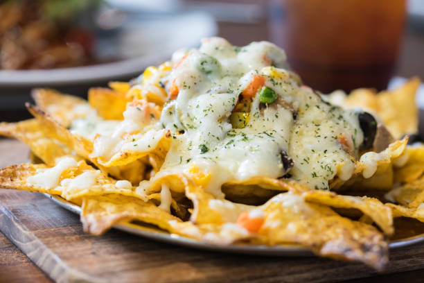 um prato de nachos deliciosa tortilha com molho de queijo derretido e molho. fundo de comida. - chili pepper guacamole food beer - fotografias e filmes do acervo