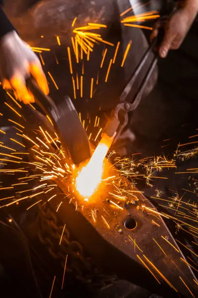 Hitting Molten Iron With a Hammer on Anvil, with Sparks Flying