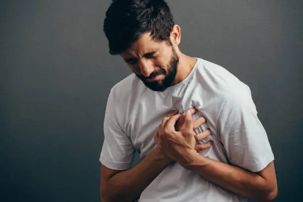 Photo of People, healthcare and problem concept - close up of man suffering from heart ache over gray background