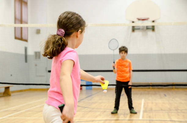 due bambini che giocano a badminton in palestra - badminton school gymnasium shuttlecock sport foto e immagini stock