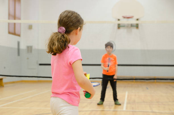 due bambini che giocano a badminton in palestra - badminton school gymnasium shuttlecock sport foto e immagini stock