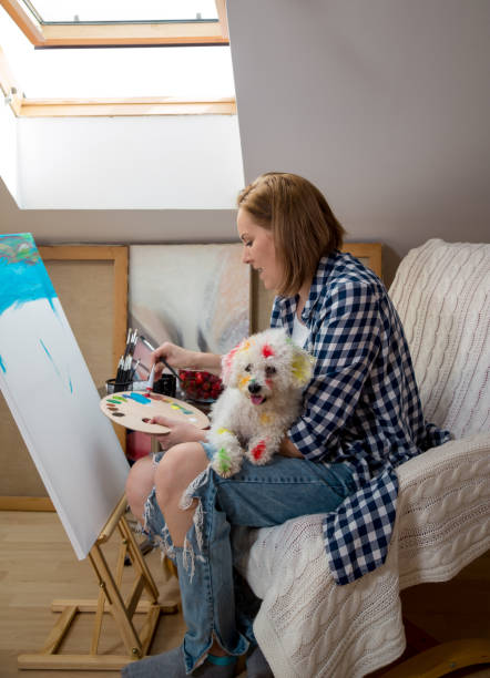 istock Happy young woman paints on canvas 890793300