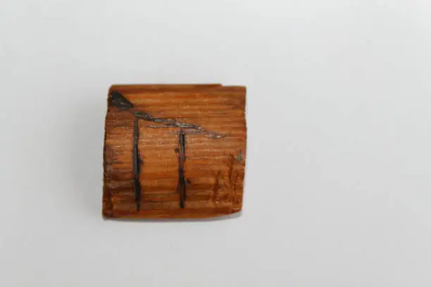 Wooden rune which means pear-tree, lie on a table on a white background