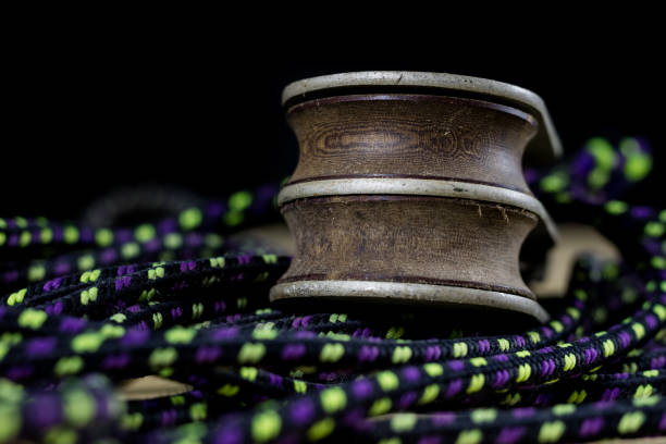 Rigging, sailing accessories. Rope block and shekel on a wooden table. Black background