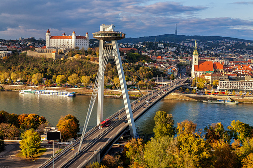 Cityscape of Bratislava with main symbols of the city: castle, SNP bridge over Danube river, St.Martin´s church and broadcast tower in background. Warm sunset light.