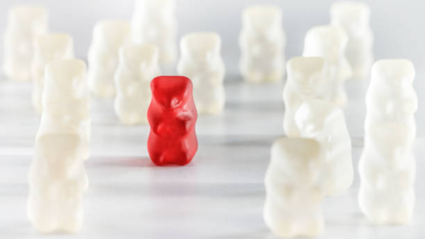 istock Red gummy bear candy standing out from the crowd arrangement close-up studio shot 890818490