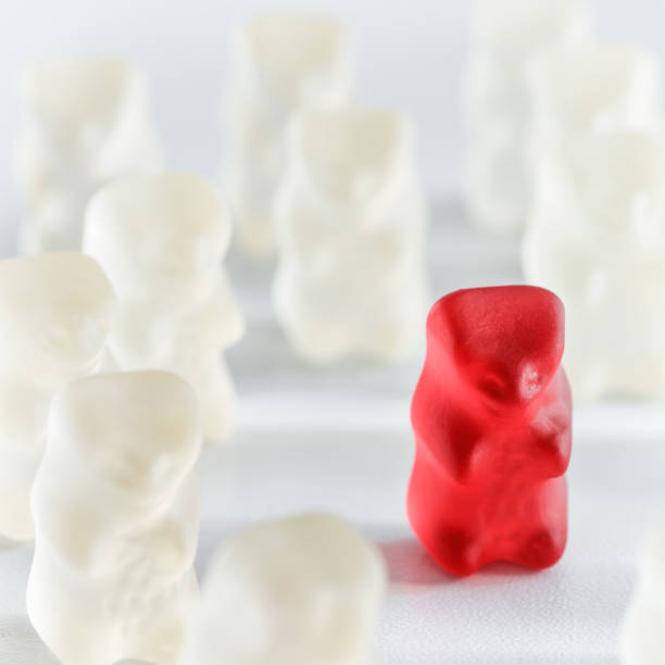 istock Red gummy bear candy standing out from the crowd arrangement close-up studio shot 890818788