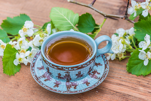 cup of tea and white horn flowers on wooden background