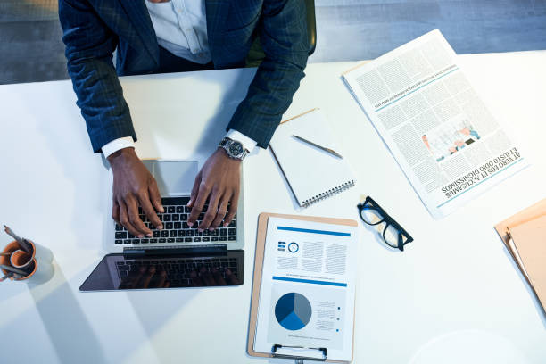 Stylish qualified manager is laboring in office Professional worker. Top view of young ambitious african businessman hands are using laptop and typing text. Man in suit is sitting at table and working on business project qualified report stock pictures, royalty-free photos & images