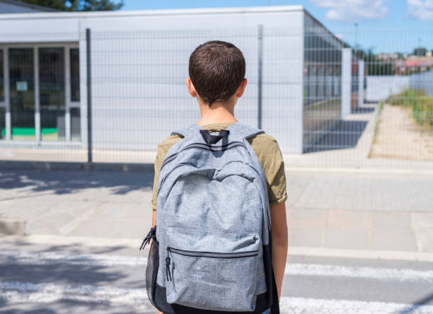 istock Teenage school boy with a backpack on his back walking to school 890847496