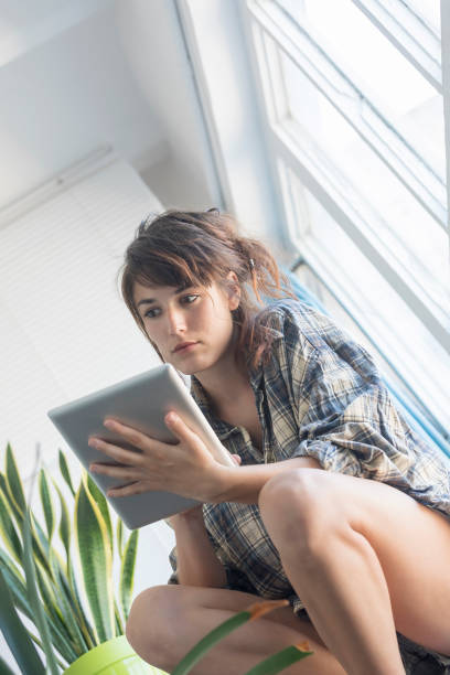 istock Woman on house stairs relaxing, reading email on a tablet 890849994