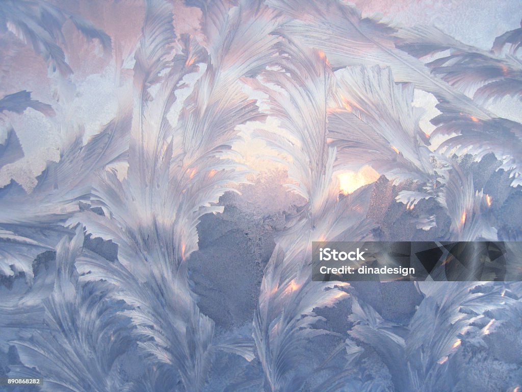 Beautiful ice pattern and sunlight on winter window glass Beautiful ice pattern and sunlight close-up on winter window glass, natural background Snowflake Shape Stock Photo