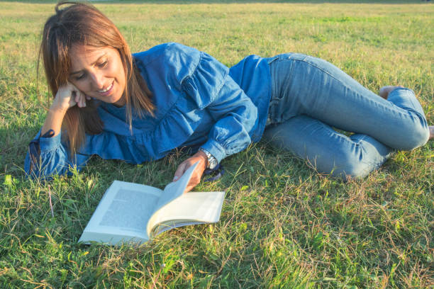 istock Smiling woman reading a  book in nature 890872910