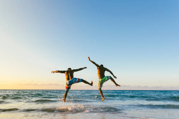 Two cuban friends having fun in the beach. Two cuban friends having fun in the beach. Friendship concept. wave jumping stock pictures, royalty-free photos & images