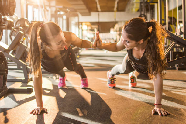 donne sportive che si danno cinque alti l'una all'altra mentre si allenano insieme in palestra. - friendship women exercising gym foto e immagini stock