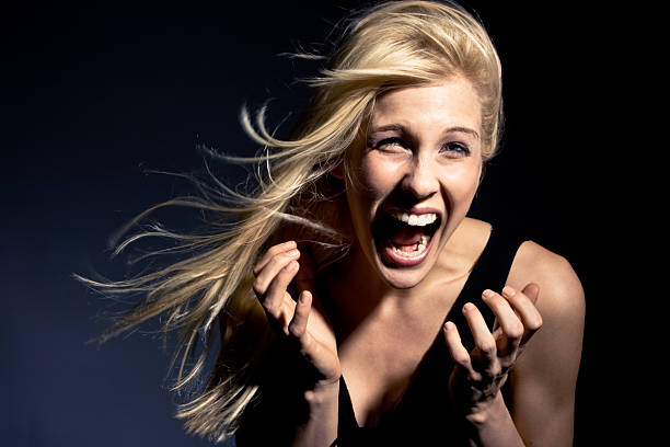 Woman in dramatic lighting screaming young blond woman screaming,  studio shot hysteria stock pictures, royalty-free photos & images