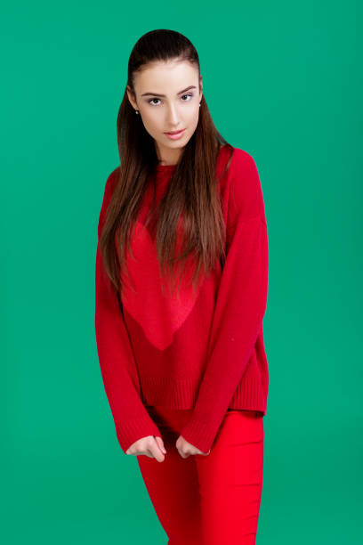 istock woman in red sweater on green background 890913866