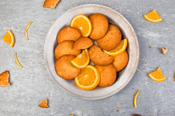 galletas y frutas cítricas naranja en la placa sobre fondo gris. endecha plana - biscotti jam biscuit cookie biscuit fotografías e imágenes de stock