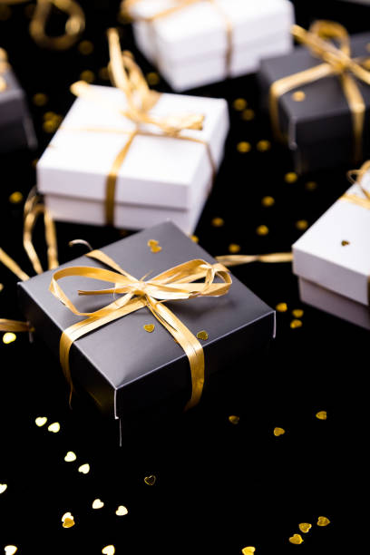 istock Black and white gift boxes with gold ribbon on shine background. Close up. 890931980