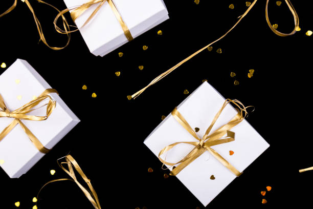 istock White gift boxes with gold ribbon on shine background. Flat lay 890931982