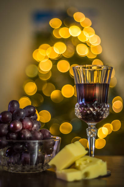 Glass half full of red wine and cheese and grapes