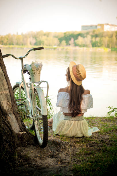 istock Romantic girl sitting under a tree by the lake 890936556